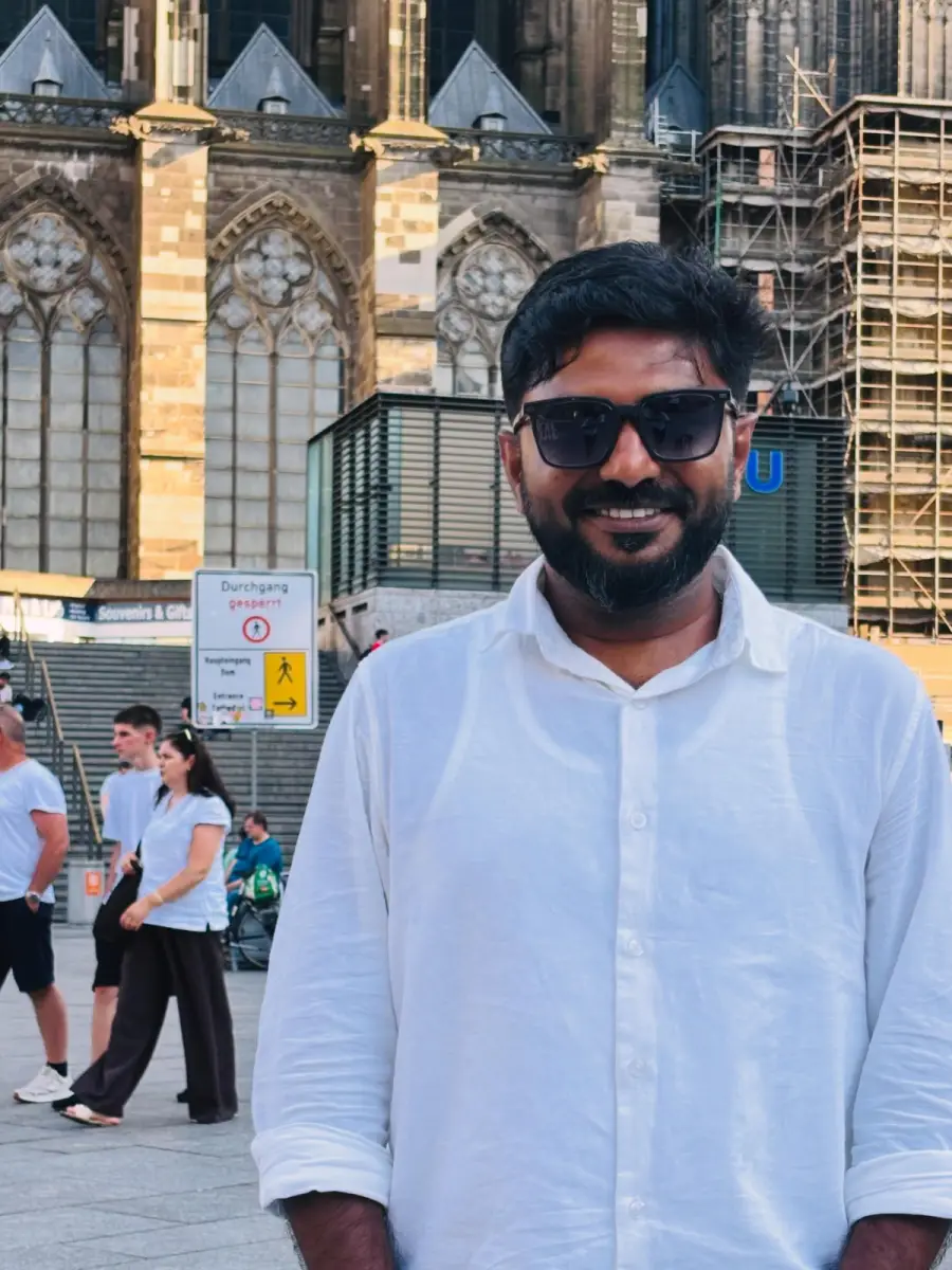 Niyas in a white shirt and sunglasses in front of Cologne Cathedral